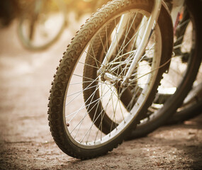 Wheels parked in the Park on a sandy road bicycles, illuminated by bright sunlight.