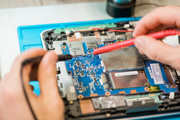 Fototapeta na wymiar Two small soldering-irons in hands of professional repairman during work