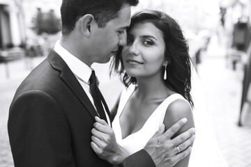 Black and white photo of cheerful emotional newlyweds who enjoy each other. Gorgeous bride and handsome groom. Luxury elegant wedding couple kissing and embracing. Romantic moment.Together. Wedding. 