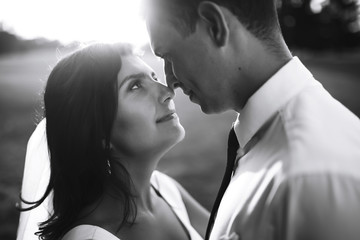 Black and white photo of cheerful emotional newlyweds who enjoy each other. Gorgeous bride and handsome groom. Luxury elegant wedding couple kissing and embracing. Romantic moment.Together. Wedding. 
