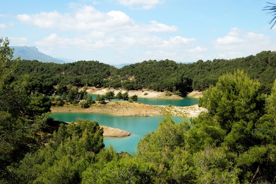 Elevated view across the treetops towards Guadalhorce lake and mountains near Ardales, Spain.