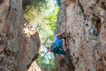 Male rock climber on challenging route in cave. Young man lead climbing in a beautiful grotto. The climber overcomes a difficult route. The athlete trains on a natural relief. Climbing in Spain.