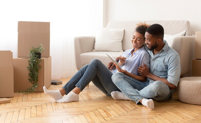 Spouses Using Tablet Sitting On Floor Among Unpacked Boxes Indoor
