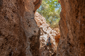 Male rock climber on challenging route in cave. Young man lead climbing in a beautiful grotto. The climber overcomes a difficult route. The athlete trains on a natural relief. Climbing in Spain.