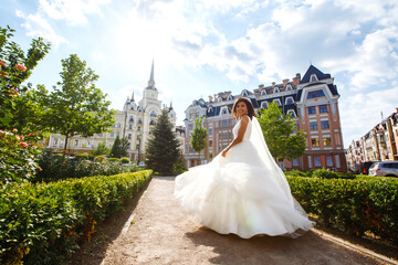 Obraz premium Young elegant bride in a white dress in the city. Beautyful bride with luxury make-up and hairstyle. Happy newlywed woman. Smiling bride. Wedding day. Fashion bride.