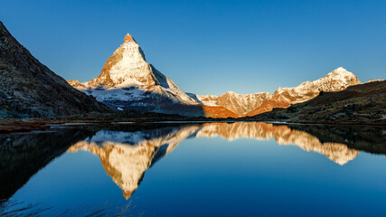 Classical Swiss view of snow-capped epic Mattergorn mountain peak reflected in Riffelsee lake....