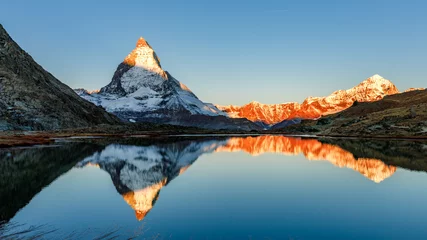 Wall murals Reflection Classical Swiss view of snow-capped epic Mattergorn mountain peak reflected in Riffelsee lake. Iconic landmark in Switzerland located near Zermatt resort. Picturesque landscape of alpenglow in Alps.