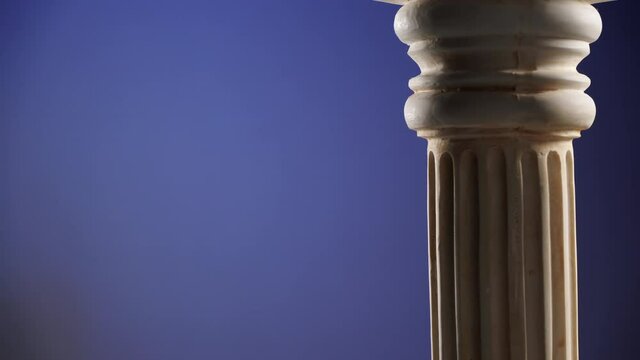 Single ancient greek column rotating slowly on dark blue background, copy space text area