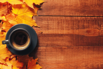 Grey cup of coffee, heap of yellow maple leaves on dark wooden table. Autumn background concept....