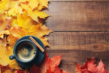 Grey cup of coffee, cinnamon, red and yellow maple leaves on dark wooden table. Autumn background concept. Fall menu, expresso, coffee shop, break, copy space, page