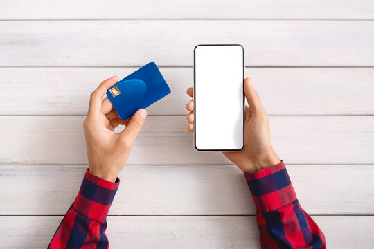 Man's hands holding credit card and blank cellphone for financial transaction