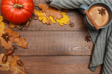 Grey cup of coffee with milk and spices, scarf, yellow oak leaves, acorns, orange pumpkins on dark...
