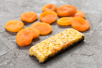  Granola bar with dried apricots on a gray background. Close-up.