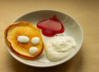 Hash browns on a plate with sour cream and raspberry jam