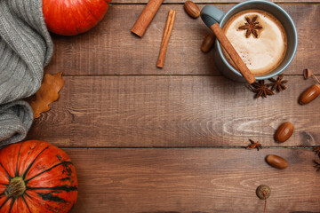 Grey cup of coffee with milk and spices, scarf, yellow oak leaves, acorns, orange pumpkins on dark...