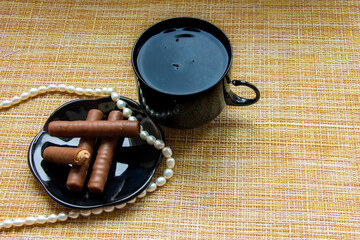 black cups with candy tea on a black plate with a string of white pearls