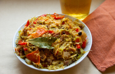 stewed cabbage with mushrooms and paprika on the background of a glass of beer