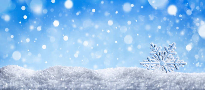 Winter snow background with decorative snowflake against blue sky. Banner format. Beautiful wintertime holiday scene.