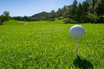 Golf Ball on tee at the teeing area. Golf course with a rich green turf beautiful scenery.