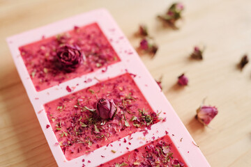 Handmade soap sprinkled by grated floral petals with small pink rosebuds on top