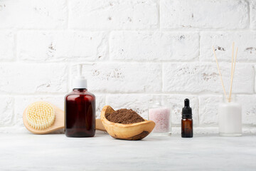 Beautiful spa relax concept. Coffee scrub, aroma diffuser, oil, brush for body massage and sea salt on white stone background.