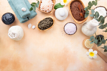 Fototapeta na wymiar Beautiful spa relax concept. Coffee with cinnamon scrub, green tea scrub, cotton pouches with herbs for massage and other Spa accessories on yellow-sand color background top view. Copy space.