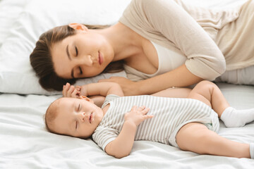 Adorable infant child sleeping with his mom in bedroom
