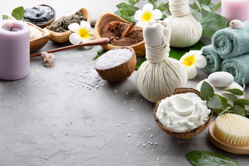 Beautiful spa relax concept. Coffee with cinnamon scrub, green tea scrub, cotton pouches with herbs for massage, sea stones and other Spa accessories on grey background.