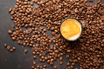 Coffee beans and a сup of coffee on a dark brown background top view.