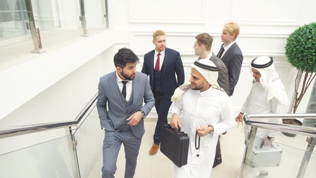 Caucasian man leads sheikh to discuss business ideas. Business center background