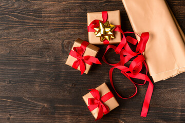 Christmas 2020 New Year 2020 Saint Valentine gift wrapping. Golden beige paper and red bow on a wooden table, family holiday. celebration atmosphere . Xmas spirit present