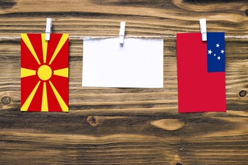 Hanging flags of Macedonia and Samoa attached to rope with clothes pins with copy space on white...