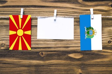 Hanging flags of Macedonia and San Marino attached to rope with clothes pins with copy space on...