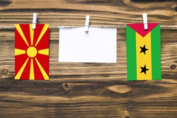 Hanging flags of Macedonia and Sao Tome And Principe attached to rope with clothes pins with copy...