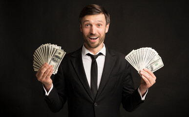 Excited Businessman Holding Money Cash Standing, Black Background, Studio Shot