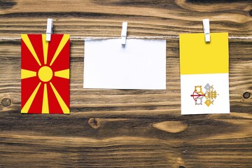 Hanging flags of Macedonia and Vatican City attached to rope with clothes pins with copy space on...