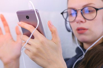 Woman listens music in headphones on smartphone and sings a song, phone close-up