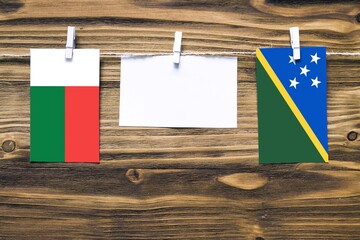 Hanging flags of Madagascar and Solomon Islands attached to rope with clothes pins with copy space...