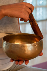  Yoga teacher playing Tibetan bowl on yoga mat