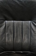 Black leather chair back rest with light textures, horizontal and vertical lines. Full frame...