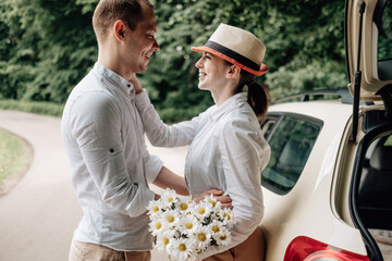 Young Happy Couple Dressed Alike in White T-shirt Having Fun Near the Car, Weekend Outside the City, Holidays and Road Trip Concept