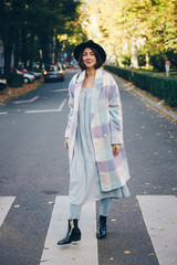 fashion blogger street style. fashionable woman posing wearing oversized checked coat, black ankle boots and a black trendy mini handbag. crossing the street. detail of a perfect fall 2019 outfit. 