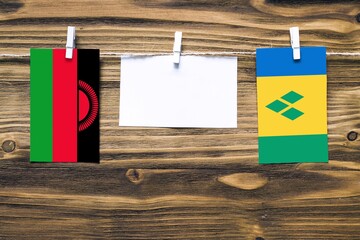 Hanging flags of Malawi and Saint Vincent And The Grenadines attached to rope with clothes pins...