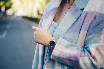 street style 2019 fashion details. close up, young fashion blogger wearing brushed oversized check pattern coat and a black and golden analog wrist watch. 