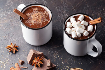 Hot chocolate with marshmallow and cinnamon stick on brown background