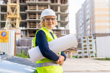 A female builder worker at a construction site works and controls the process.