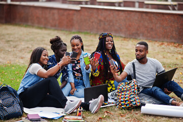 Group of five african college students spending time together on campus at university yard. Black afro friends making with mobile phones. Education theme.