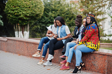 Group of five african college students spending time together on campus at university yard. Black afro friends studying. Education theme.