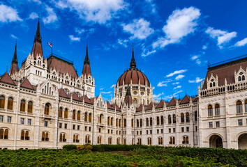 Fototapeta na wymiar Daytime close up view of historical building of Hungarian Parliament in Budapest, Hungary, Europe with hungarian national flag on background of bright blue cloudy sky
