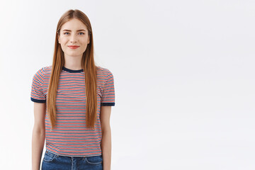 Fototapeta premium Cheerful good-looking, confident european woman in striped t-shirt with long fair hair, hold hands, act obedient and ready, self-assured can tackle any task, standing white background positive